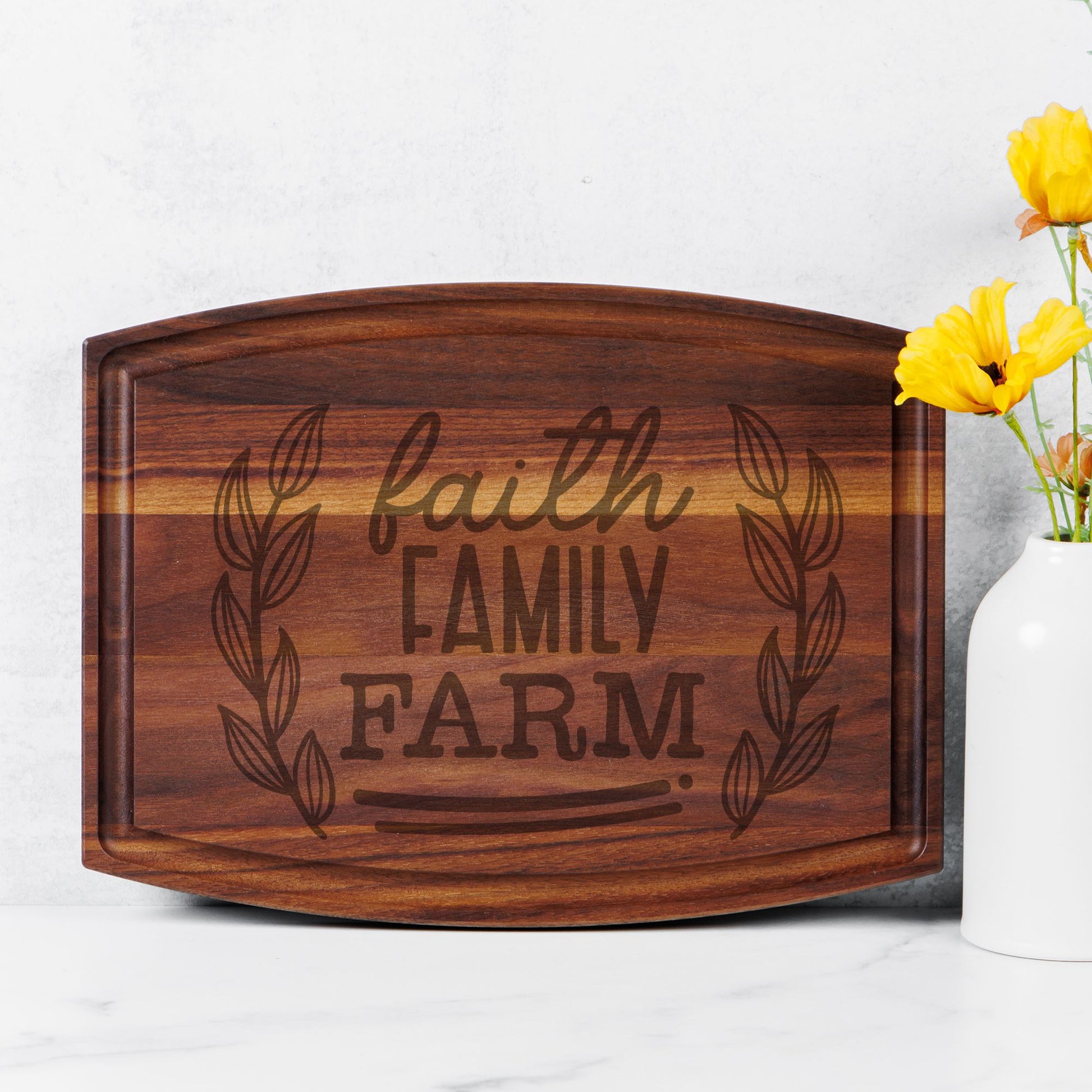 image of walnut cutting board on white countertop with yellow flowers