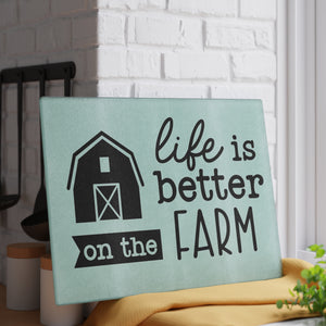 glass cutting board with the words "life is better on the farm" against a white brick wall