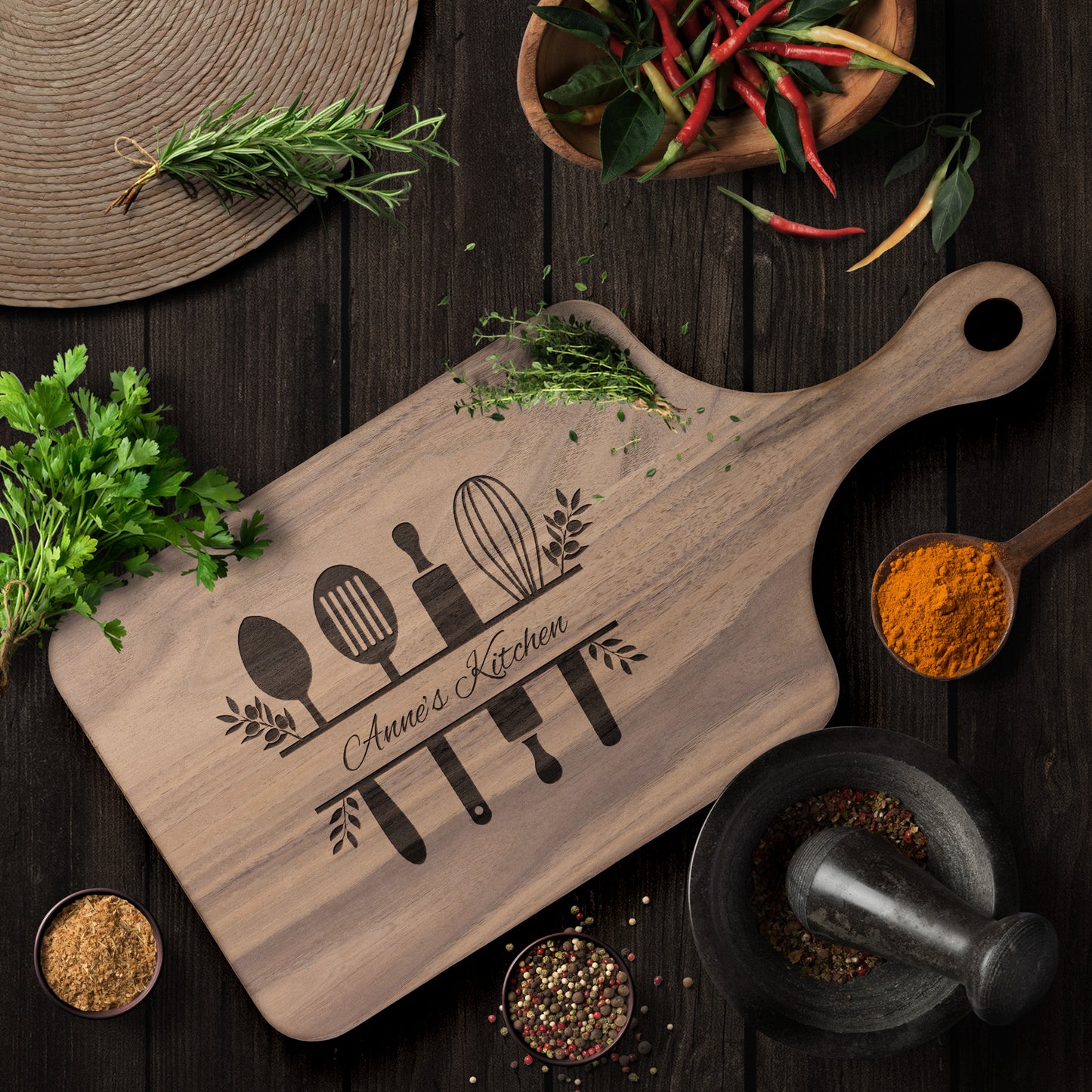 view of personalized walnut paddle cutting board on a dark brown table with herbs and spices as decoration