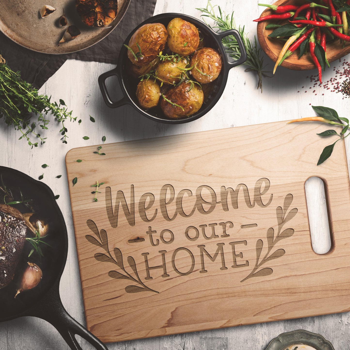 view of maple cutting board with the words "welcome to our home" on a white table with potoatoes and spices as decoration